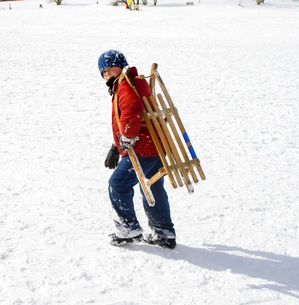 Menino jovem escorregando pela colina na neve, inverno branco — Fotografia de Stock