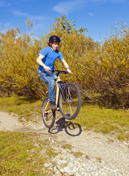 Garçon saute avec son vélo de saleté sur les rampes naturelles — Photo