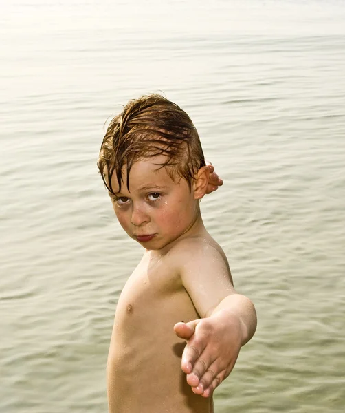 Niño está posando orgullosamente mientras está de pie en el mar frío —  Fotos de Stock