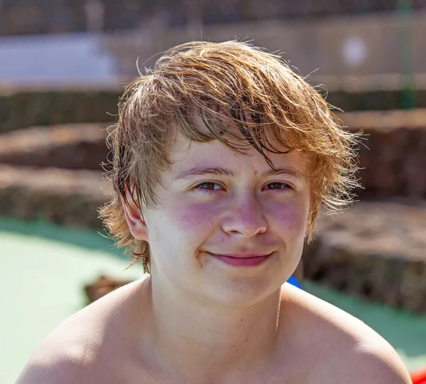 Χαριτωμένο αγόρι κάθεται στο χώρο της πισίνας μετά το κολύμπι — Φωτογραφία Αρχείου