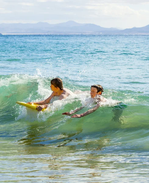 Rapazes divirtam-se a surfar nas ondas — Fotografia de Stock