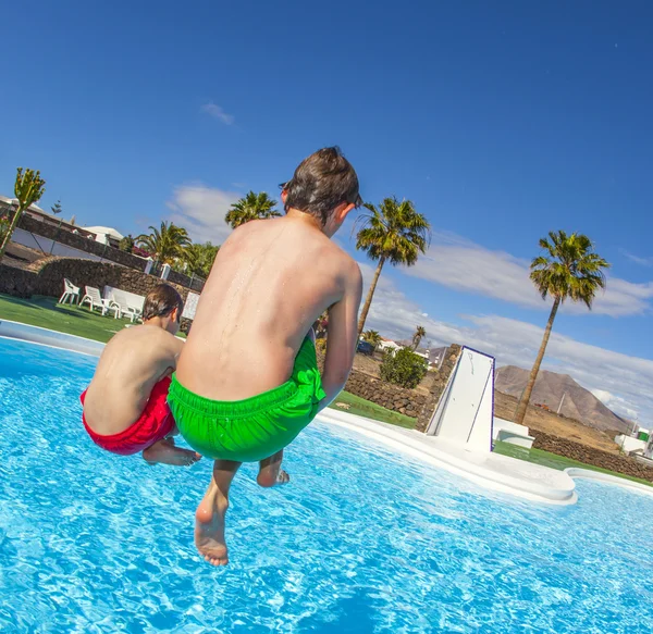 Rapaz a saltar para a piscina azul — Fotografia de Stock