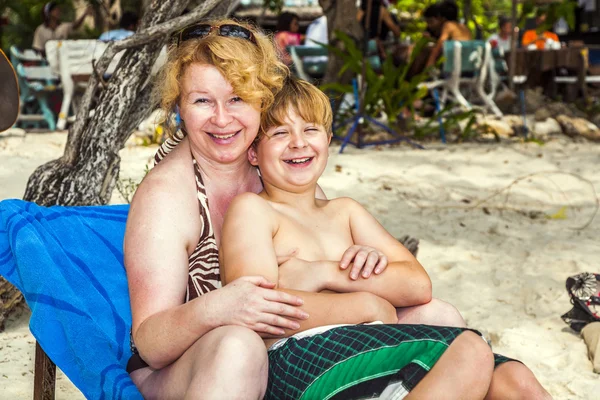 Madre abrazando con joven hijo en la silla de playa —  Fotos de Stock