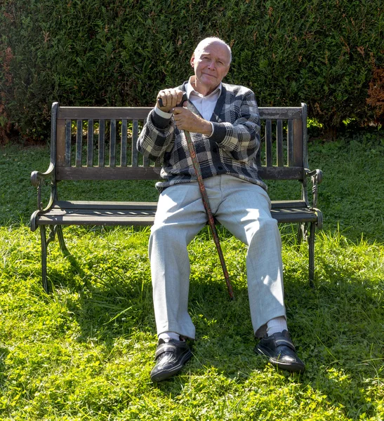 Onun bahçesinde bir bankta oturan yaşlı adam sahiptir — Stok fotoğraf