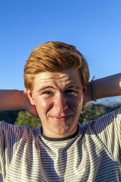 Πορτρέτο του όμορφου αγοριού με κόκκινα μαλλιά κάτω από τον γαλάζιο ουρανό — Φωτογραφία Αρχείου
