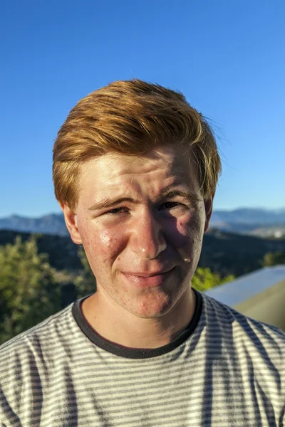 Portret van knappe jongen met rood haar onder de blauwe hemel — Stockfoto