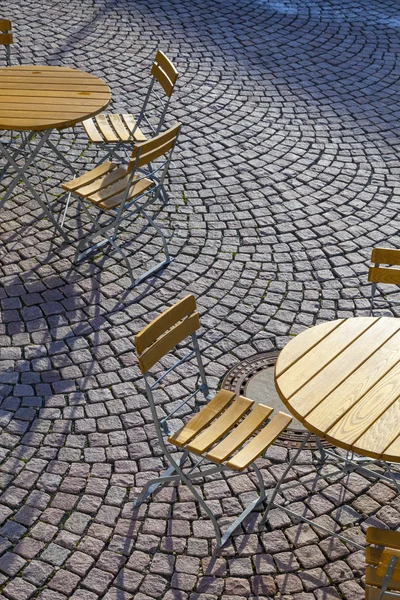 Venkovní německé café sezení s kulatými stoly a dřevěné židle — Stock fotografie