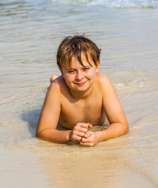 Çocuk sahilde yatan ve su ve kendini arıyor hoşlanıyor