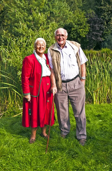 Ouderen paar staande hand in hand in hun tuin — Stockfoto