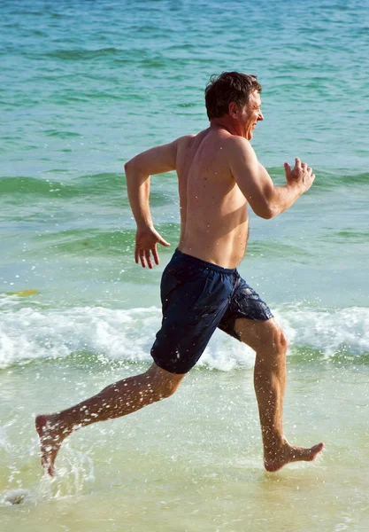 Mann läuft am schönen Strand entlang und genießt das Wasser — Stockfoto