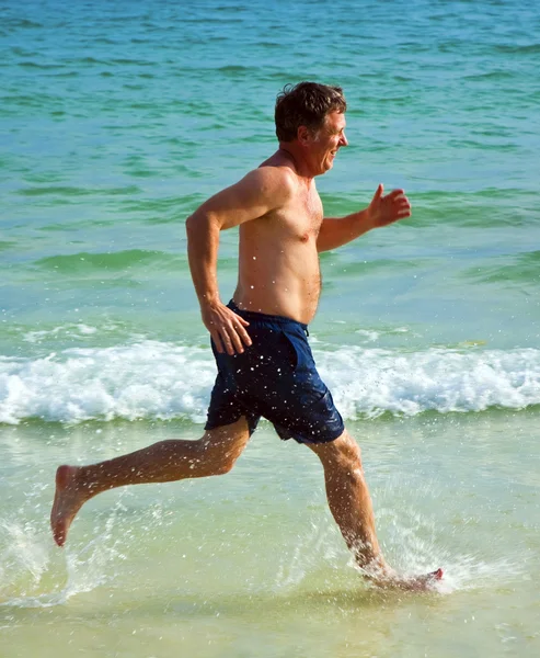 Mann läuft am schönen Strand entlang und genießt das Wasser — Stockfoto