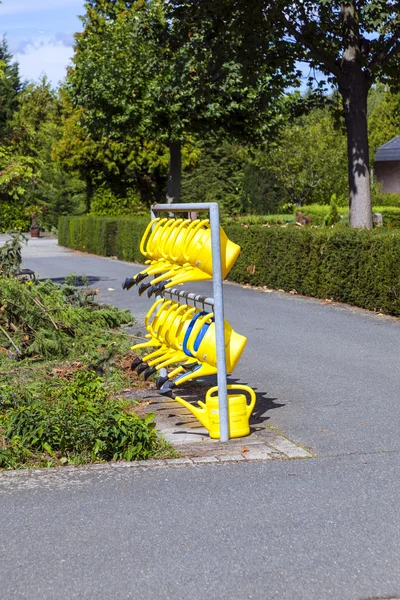 Watering cans hanging for use at the cemetery — Stock Photo, Image