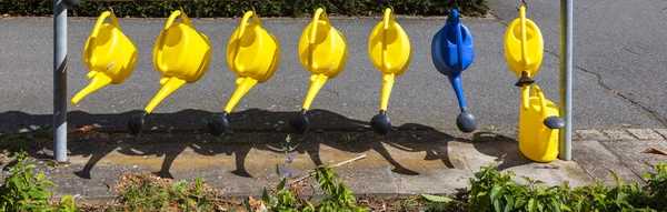 Watering cans hanging for use at the cemetery — Stock Photo, Image