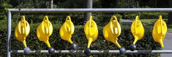 Watering cans hanging for use at the cemetery — Stock Photo, Image