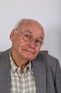 Koltuğunda oturan kendinden emin yaşlı bir adamın portresi.