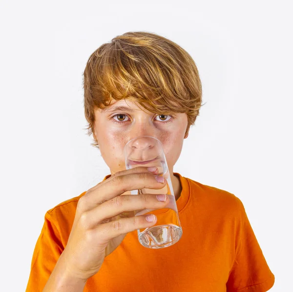 Netter Junge mit orangefarbenem Hemd trinkt Wasser — Stockfoto