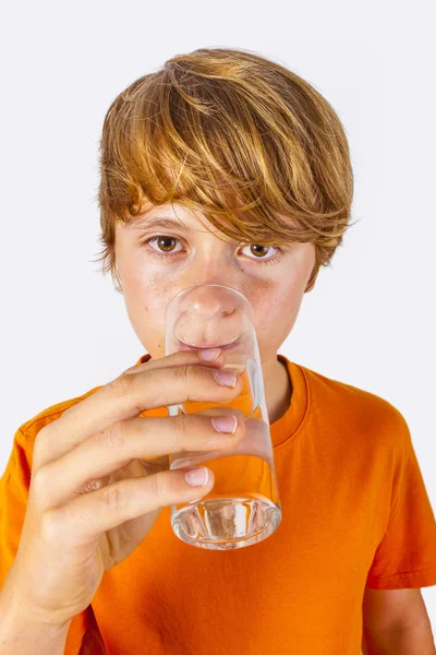 Söt pojke med orange skjorta dricker vatten Stockfoto