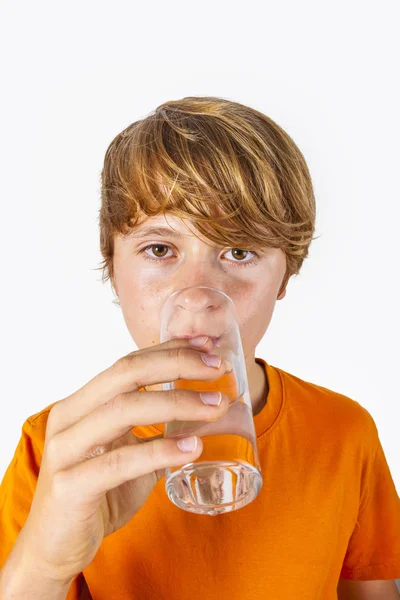 Schattige jongen met oranje shirt water drinkt Stockafbeelding