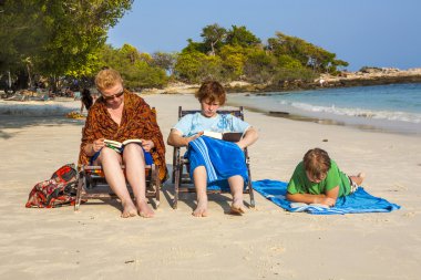 family is enjoying the sun and relaxing and reading books at the clipart