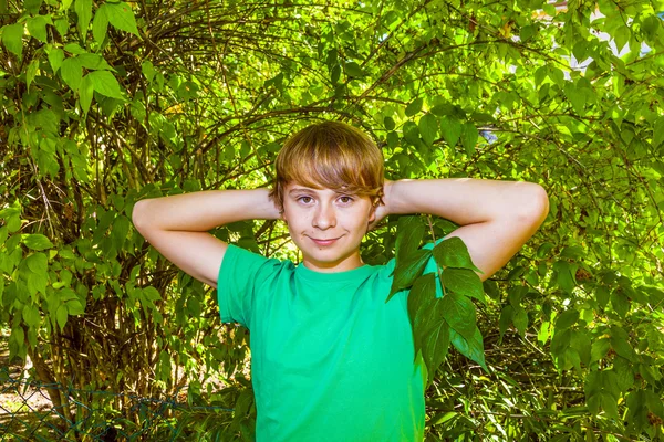 Leuke slimme jongen in de tuin onder de boom — Stockfoto