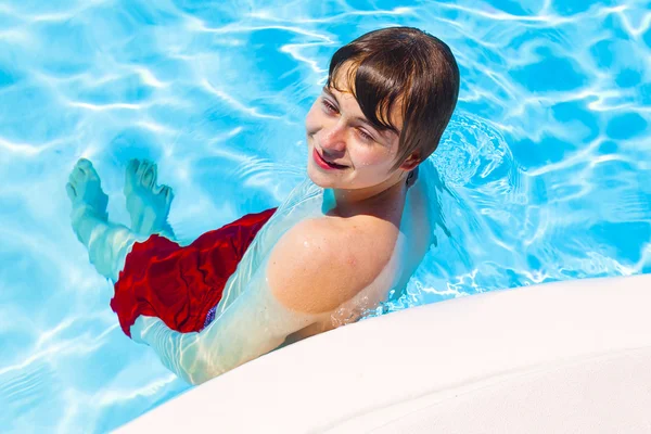 Lindo guapo adolescente descansa la piscina — Foto de Stock