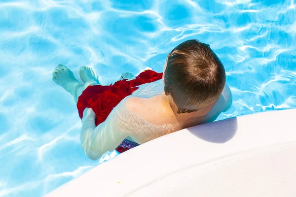 Lindo guapo adolescente descansa la piscina — Foto de Stock