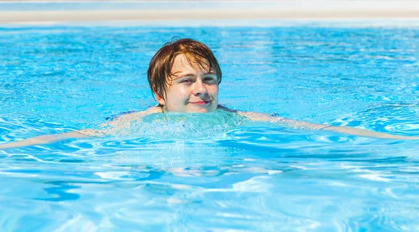 Söt vacker tonårspojke simmar i poolen — Stockfoto