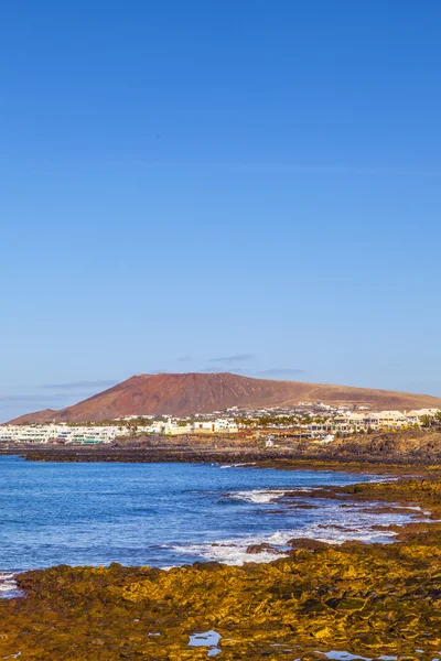 Stranden och byn playa blanca med vulkanen montana roja — Stockfoto