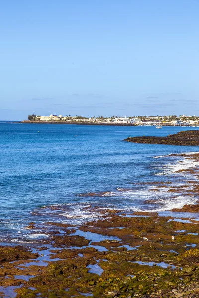 Strand en dorpje van playa blanca met de vulkaan montana roja — Stockfoto