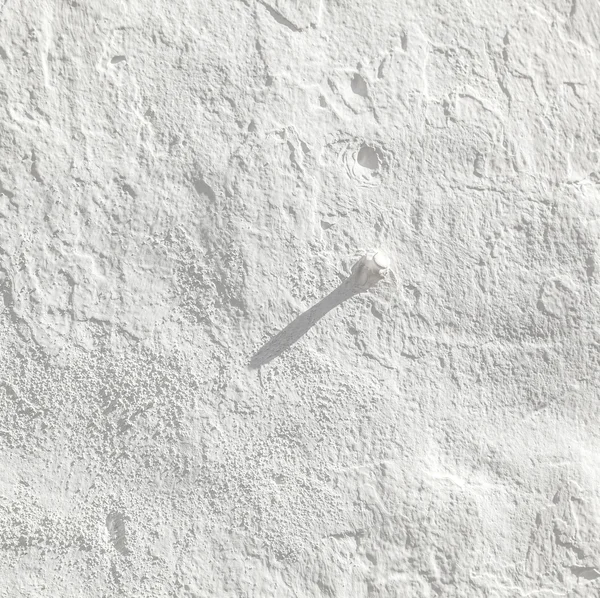 Белый фон стены с ногтем — стоковое фото