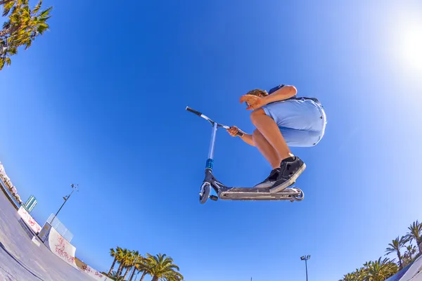 Menino pula com sua scooter sobre uma rampa — Fotografia de Stock
