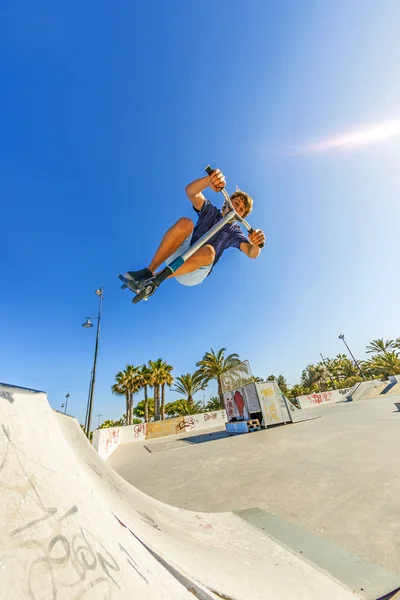 Menino pula com sua scooter sobre uma rampa — Fotografia de Stock