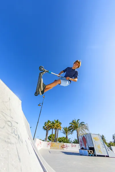 Chico salta con su scooter sobre una rampa — Foto de Stock