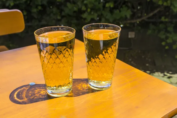 Cidre γυαλιά που στέκεται σε ένα υπαίθριο τραπέζι στον ήλιο ως σύμβολο — Φωτογραφία Αρχείου