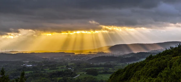 golden sunset at the mountains of the saarland with dark rain c