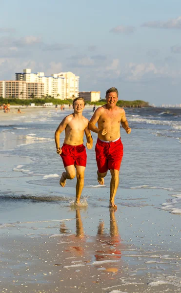 Vater und Sohn joggen gern am Strand entlang — Stockfoto