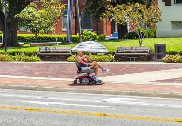 Attracive lady rides in her electric wheelchair with a parasol — Stock Photo, Image