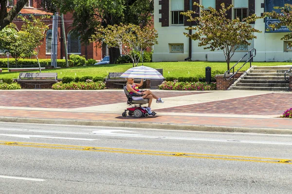 Attracive lady rides in her electric wheelchair with a parasol — Stock Photo, Image