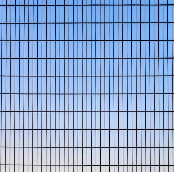 Staket med rutnätsstruktur med blå himmel i bakgrunden — Stockfoto