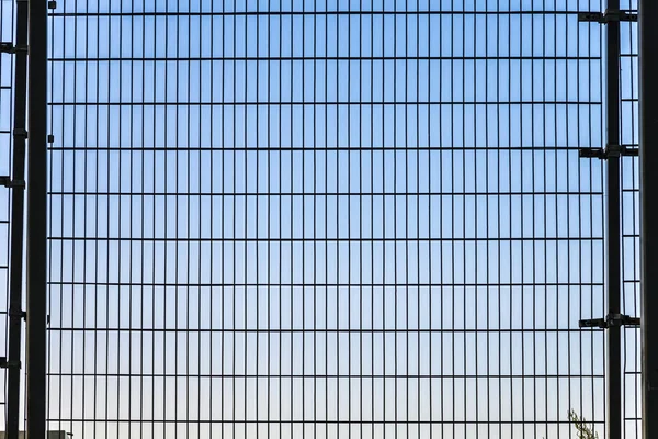 护栏网具有网格结构与背景中的蓝色天空 — 图库照片