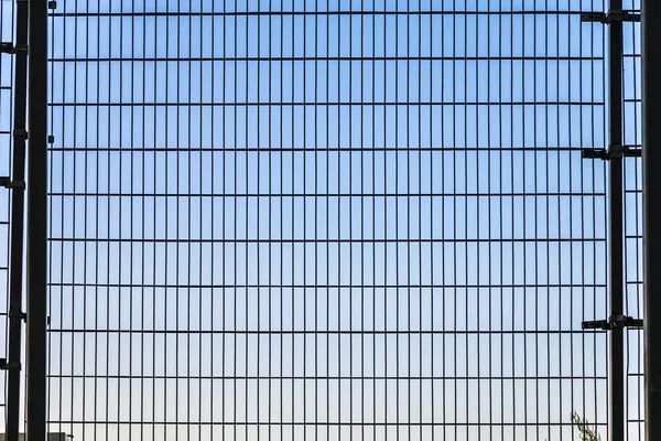 Cerca con estructura de rejilla con cielo azul en el fondo —  Fotos de Stock