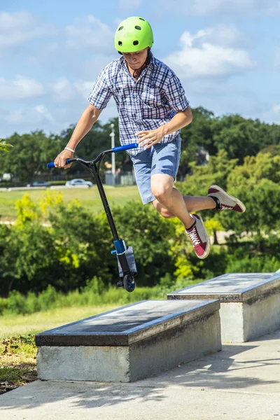 Menino se diverte montando sua scooter push no parque de skate — Fotografia de Stock