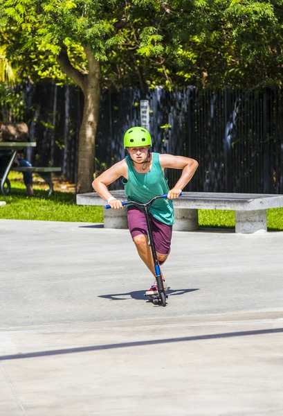 Ragazzo si diverte cavalcando la sua spinta scooter al parco skate — Foto Stock