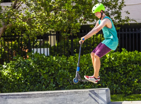 Menino se diverte montando sua scooter push no parque de skate — Fotografia de Stock