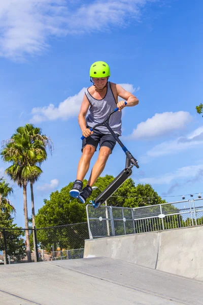 Ragazzo si diverte cavalcando la sua spinta scooter al parco skate — Foto Stock