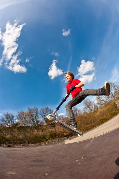 Pojken hoppar med en skoter över en funbox — Stockfoto