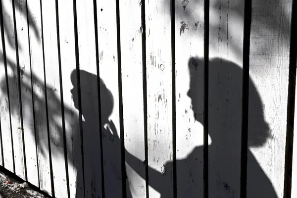 Schaduw van een jongen met moeder op een houten hek — Stockfoto