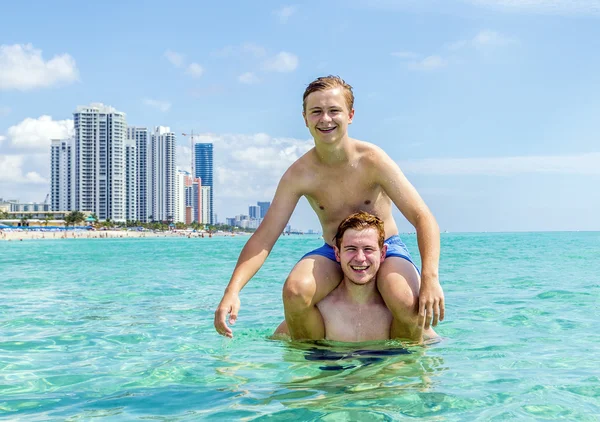 Adolescente se divertir jogando piggyback no oceano — Fotografia de Stock