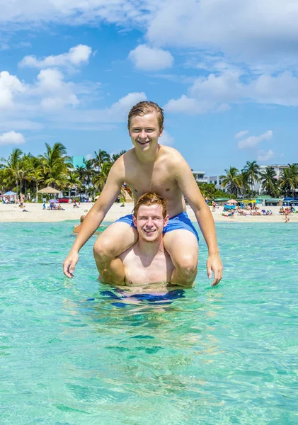 Teenager haben Spaß beim Huckepack-Spielen im Ozean — Stockfoto