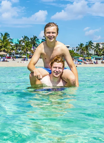 Teen have fun playing piggyback in the ocean — Stock Photo, Image